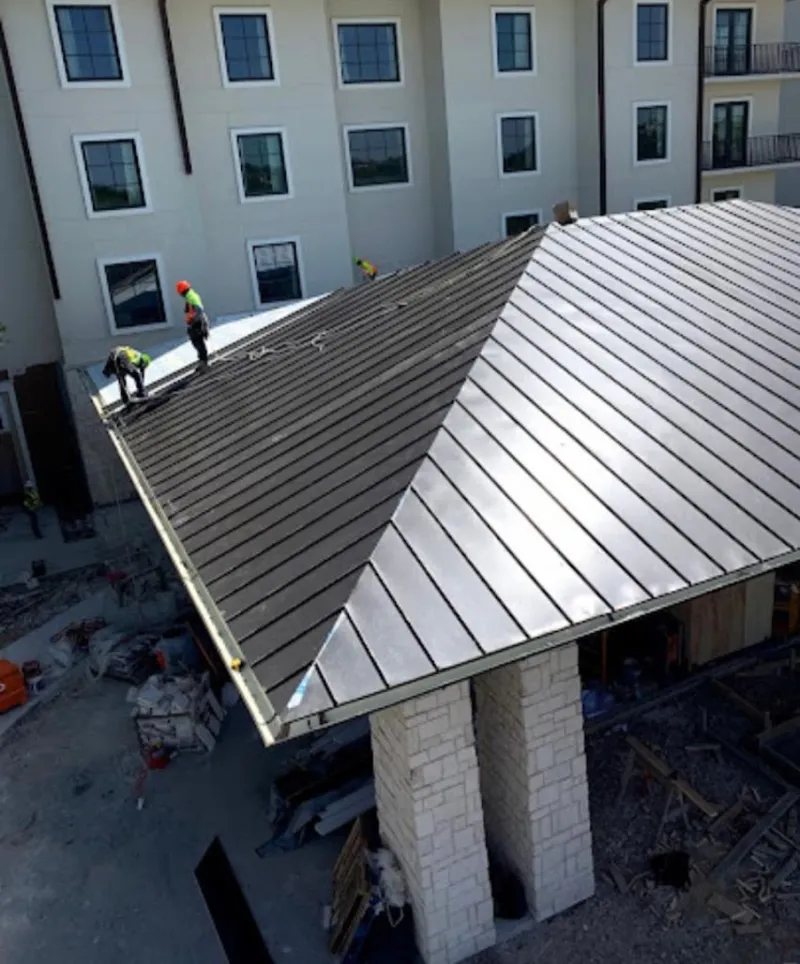 Crew installing standing seam metal roof panels on a commercial project in Dolton